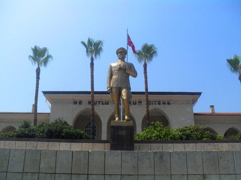 Ein Atatürk-Denkmal vor einem Gebäude und der türkischen Flagge in Mersin
