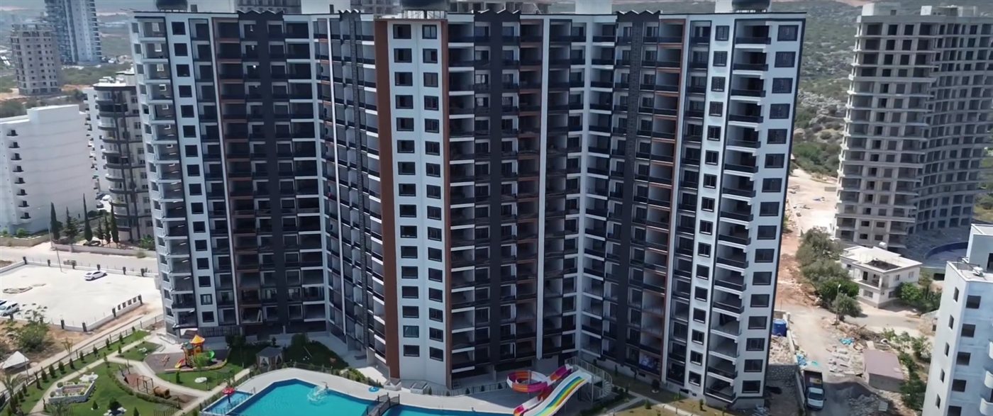 An aerial view of a residential tower with a pool and a water slide in Ayaş, Mersin