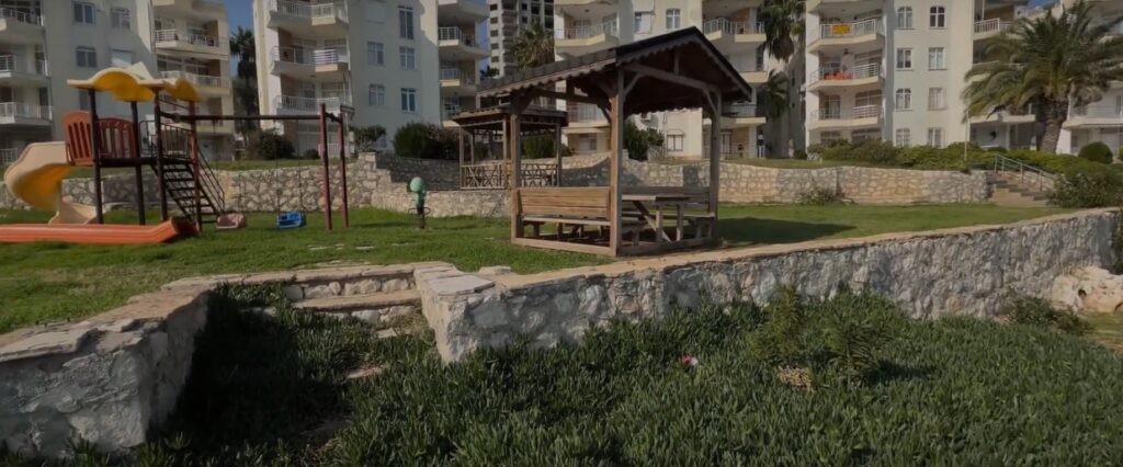 Mersin Ayaş'ta bir konut sitesinin bahçesinde çocuk oyun alanı ve ahşap çardak