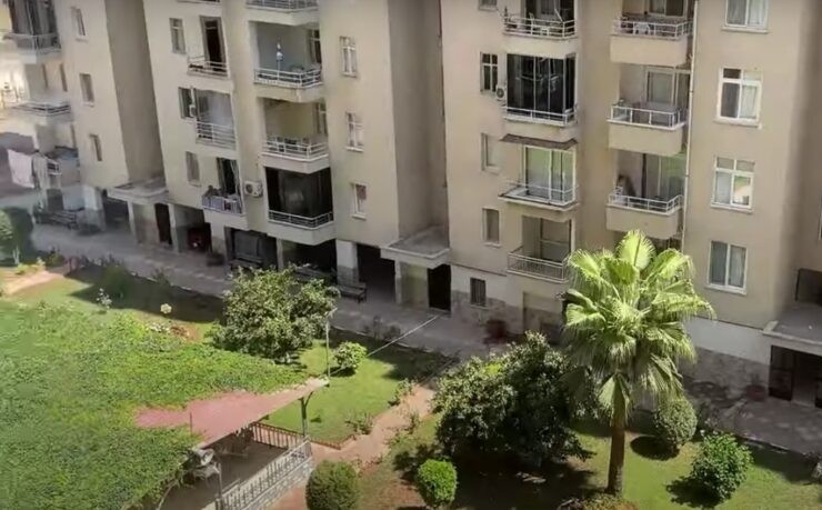 Tömük'te palmiyeli ve konut bloklu bir konut sitesinin yeşil bahçesi