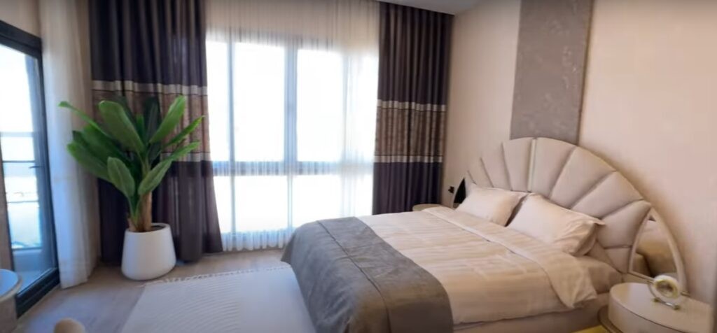 Ein helles Schlafzimmer mit großen Fenstern in einem neuen Haus in Mezitli, Mersin